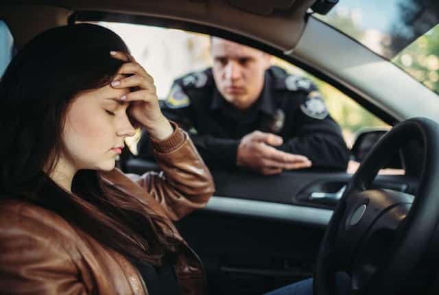 駐車違反の取締りを受けて頭を抱える女性